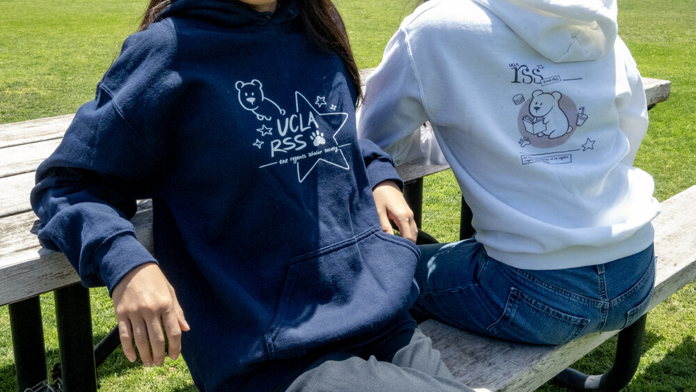 Two students on a bench wearing The Bruin Collection RSS hoodies